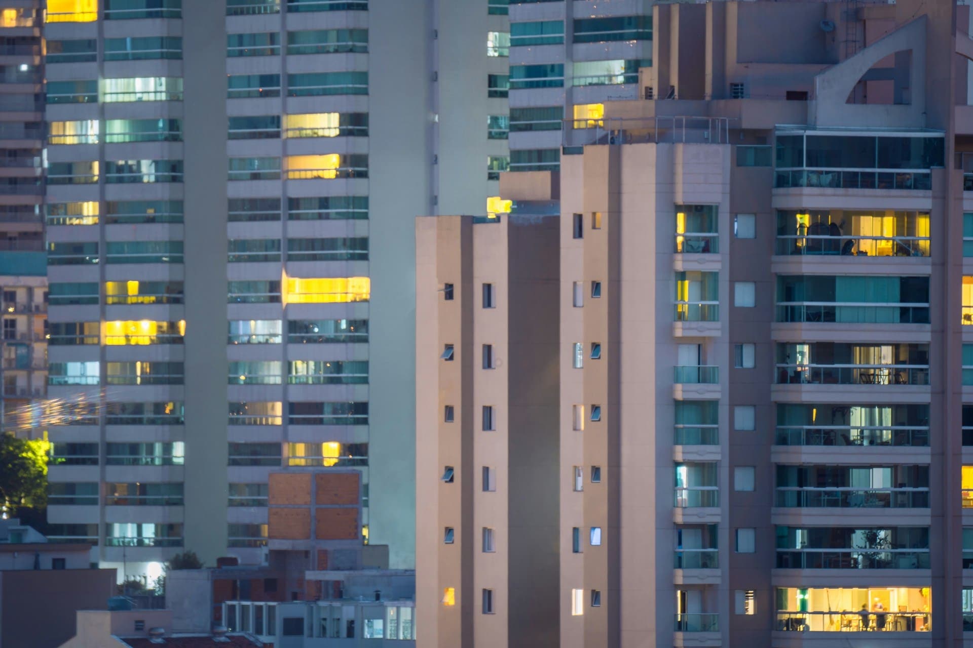 Vista de prédios residenciais iluminados ao entardecer em São Bernardo do Campo-SP, destacando a verticalização e a urbanização da cidade.