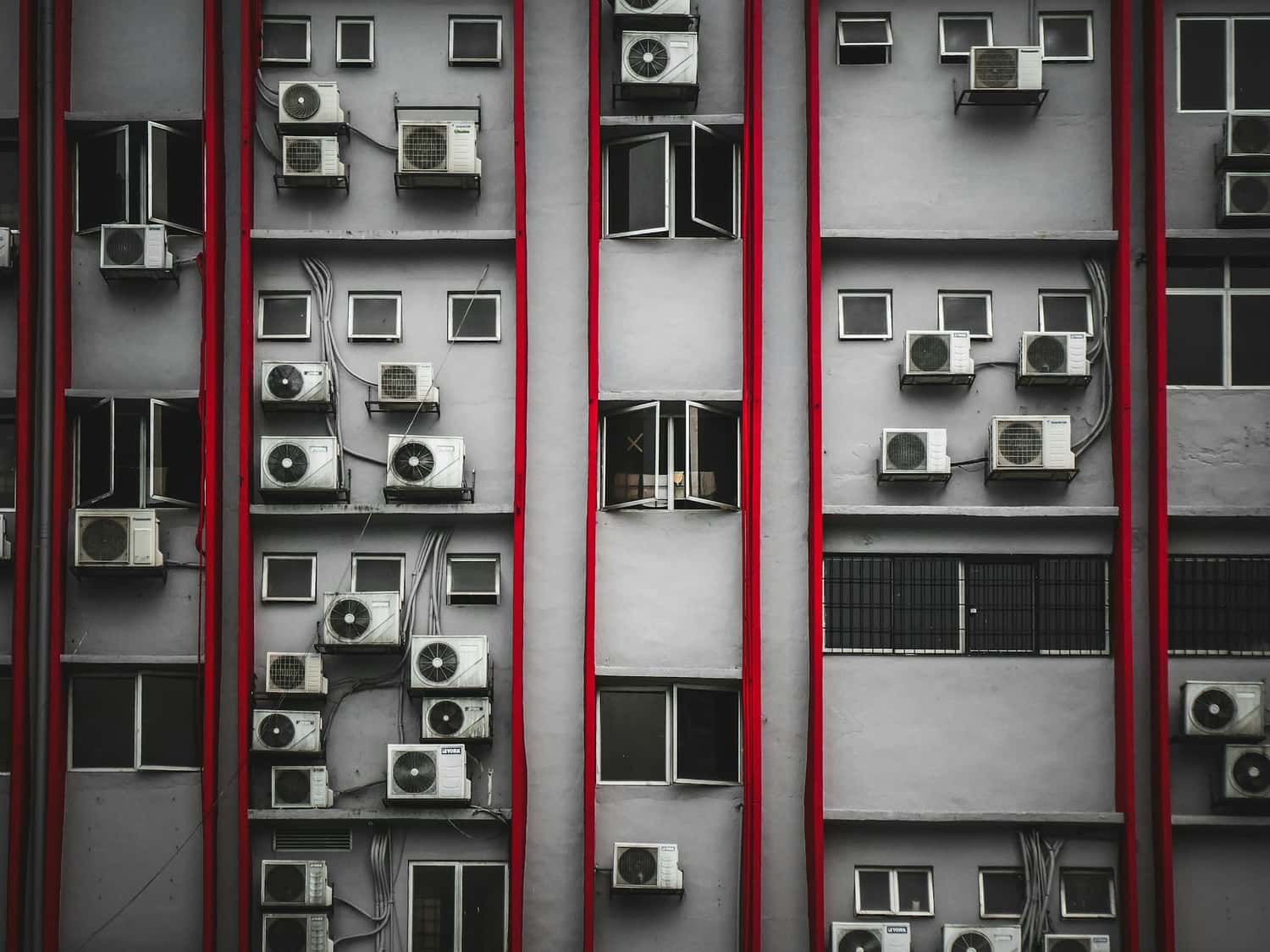 Fachada de prédio com dezenas de unidades externas de ar-condicionado instaladas, ilustrando a alta demanda por ar condicionado para apartamento em ambientes urbanos.