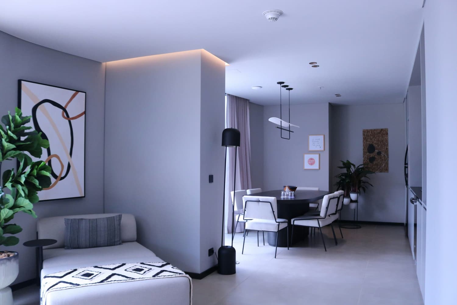 Sala de estar e jantar de um apartamento decorado, com móveis modernos, iluminação suave e elementos de design contemporâneo.