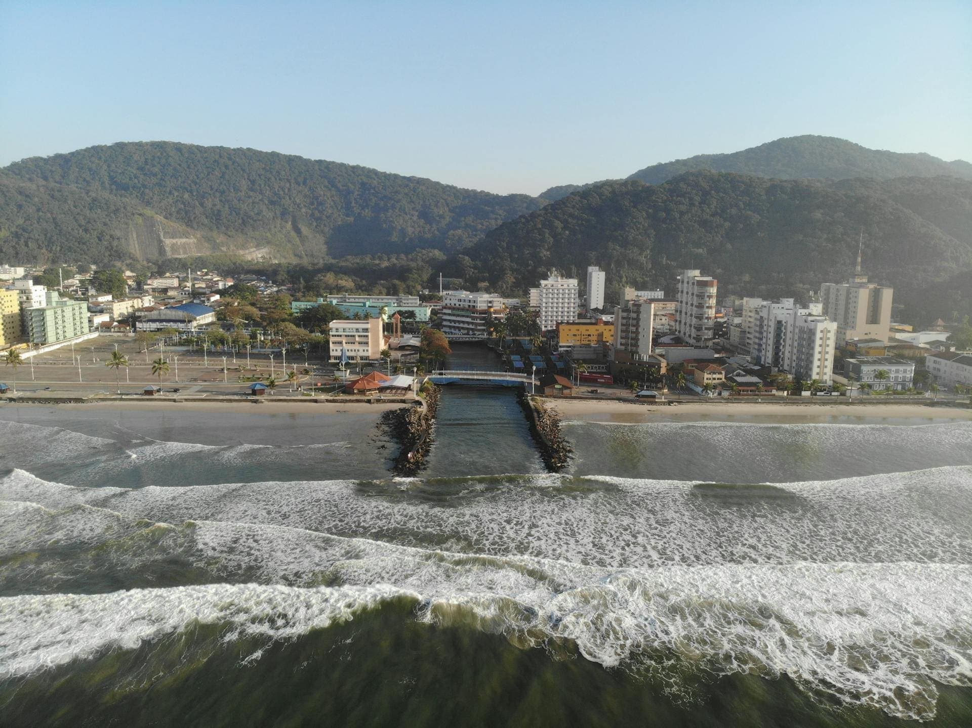 Vista aérea de uma cidade litorânea com prédios residenciais e comerciais à beira-mar, representando a oferta de imóveis no litoral.