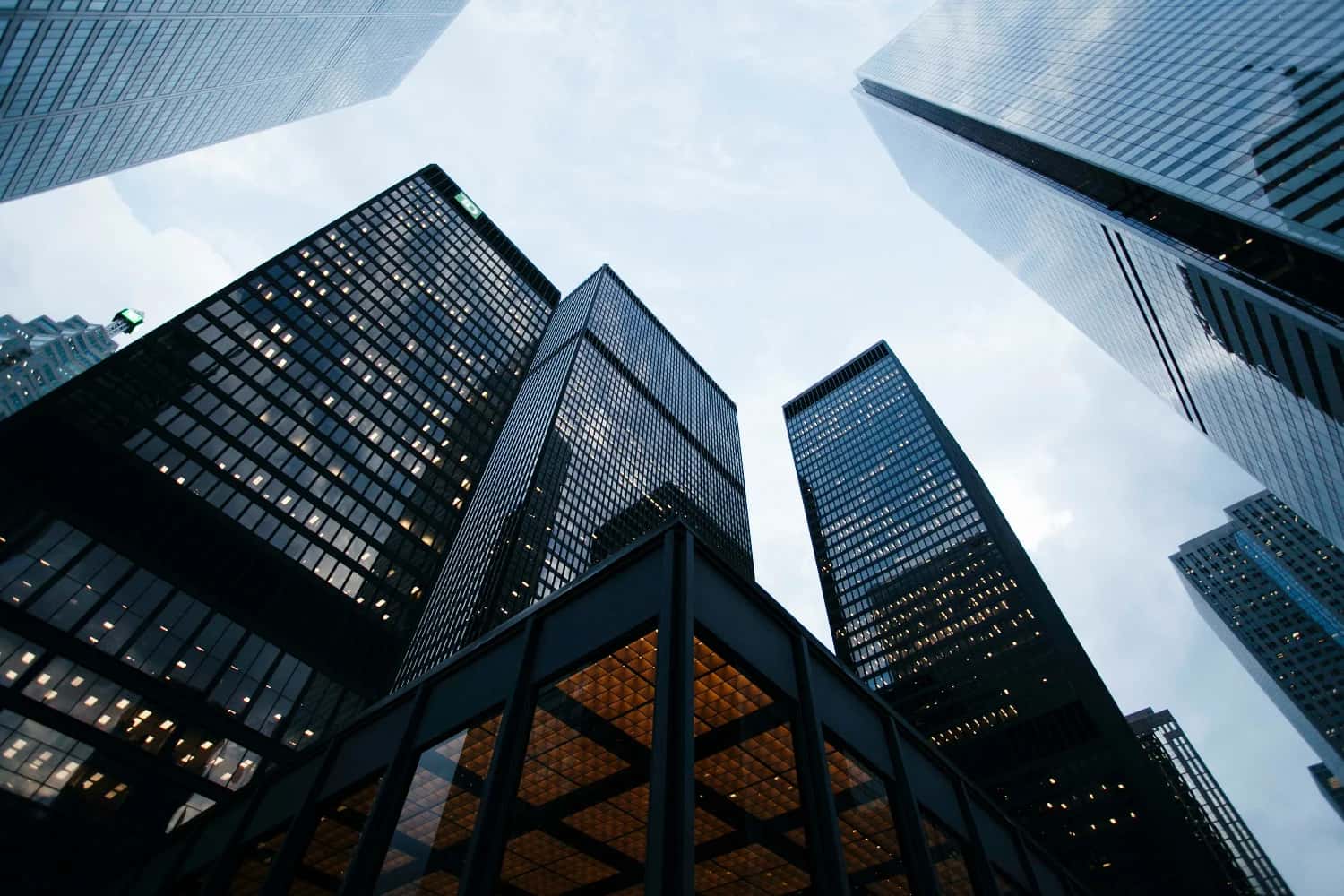 Fotografia de edifícios vistos de baixo para cima, com o céu acima deles.